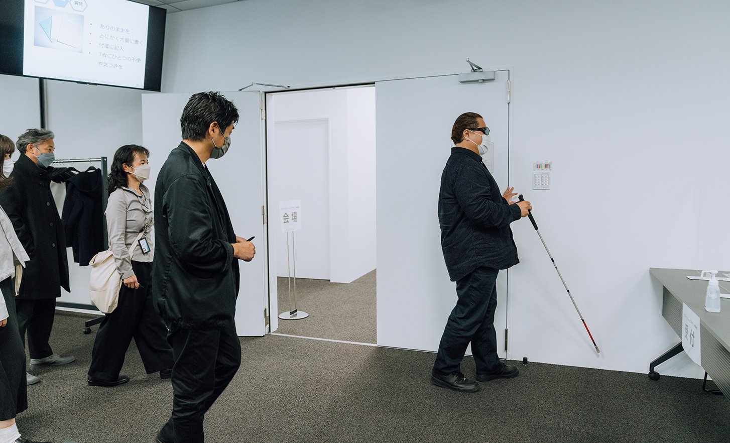 Employees watching lead user with white cane is walking in the conference room