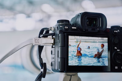 Usage image of the camera mounted on a tripod and connected to LAN cable, shooting water polo game with live view image displayed on LCD monitor