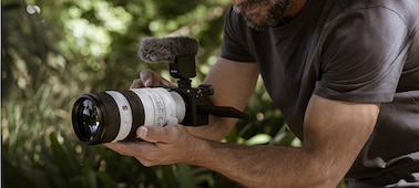 Photo of a man shooting a video with a microphone attached to the camera