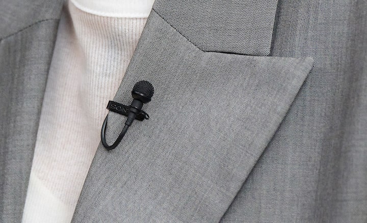 Usage image of a woman with an ECM-L1 microphone with metal windscreen on her suit lapel