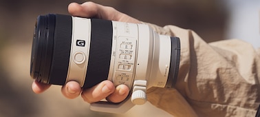 Usage image showing lens body held in palm of user’s hand, emphasising compact size